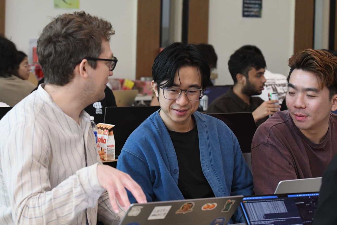 Three students at their laptops, talking over what is on screen